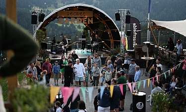 SecretGarden (C) Michale Zumsteg | Ferienregion Lenzerheide Des gens se tiennent devant une scène et font la fête avec un groupe de musique.