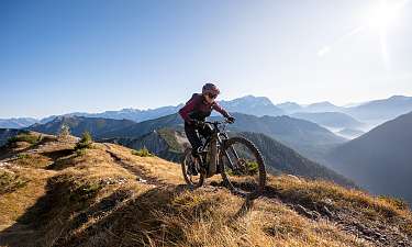 Mountainbiker auf einem alpinen Trail in der Lenzerheide mit weiter Aussicht über die Berglandschaft