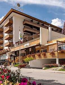 Aussenansicht des Sunstar Hotels in Lenzerheide mit blühender Umgebung und Sonnenterrasse