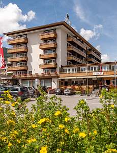 Aussenansicht des Sunstar Hotels in Lenzerheide mit Blumen im Vordergrund und Parkplatz vor dem Gebäude
